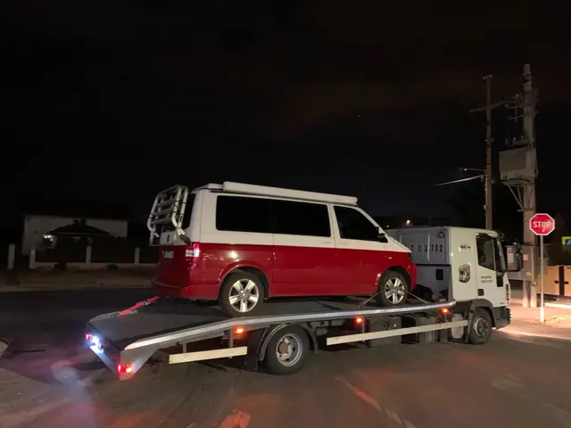 Kombi utovaren na platformu šlep vozila u večernjim satima